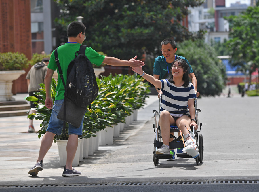 一名坐轮椅的考生离开四川师大附中考点时,与她的老师击掌