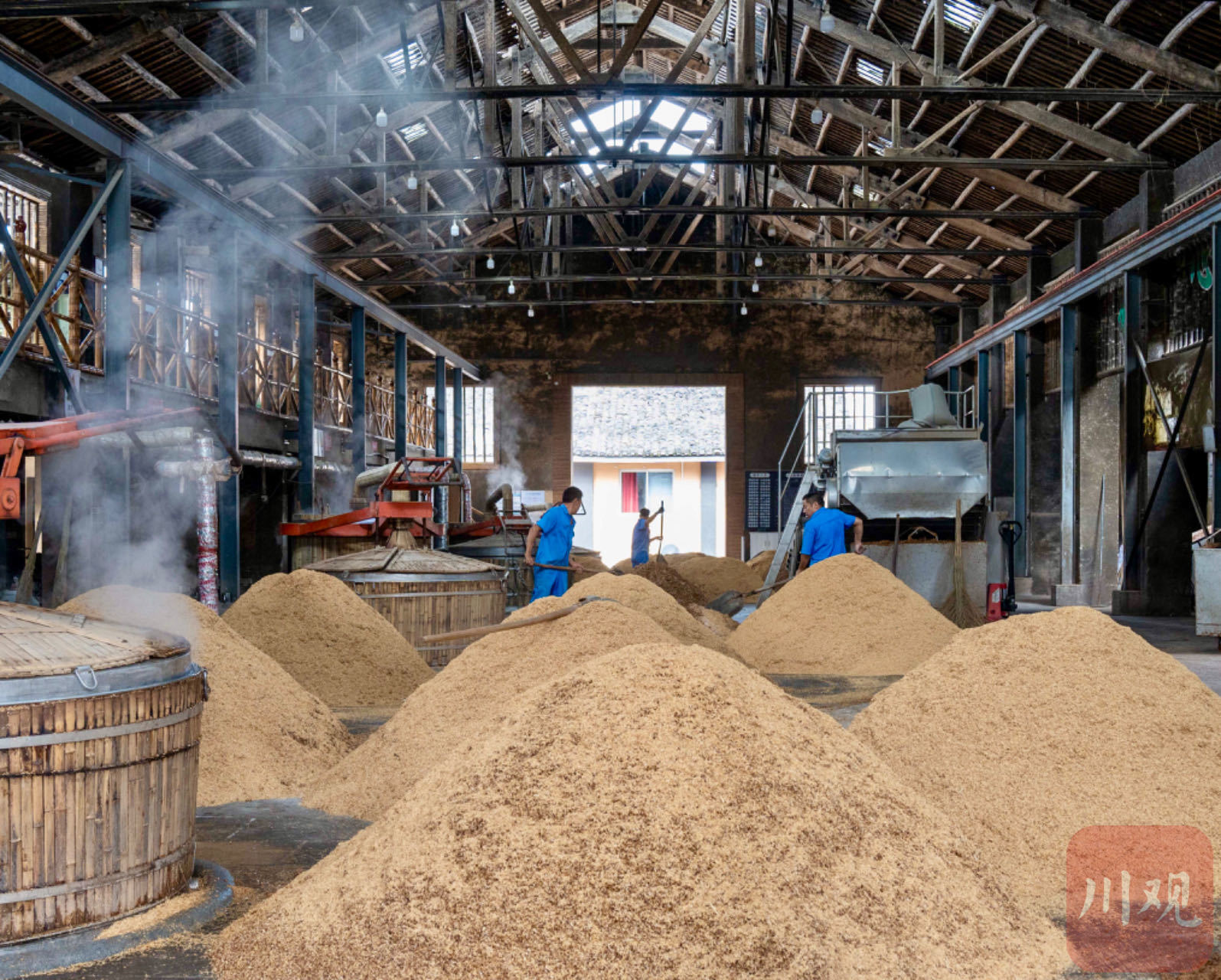 门外,浓郁的酒香顺着木门飘出,蒸汽萦绕间,酿酒师傅将酒糟铲入甑桶